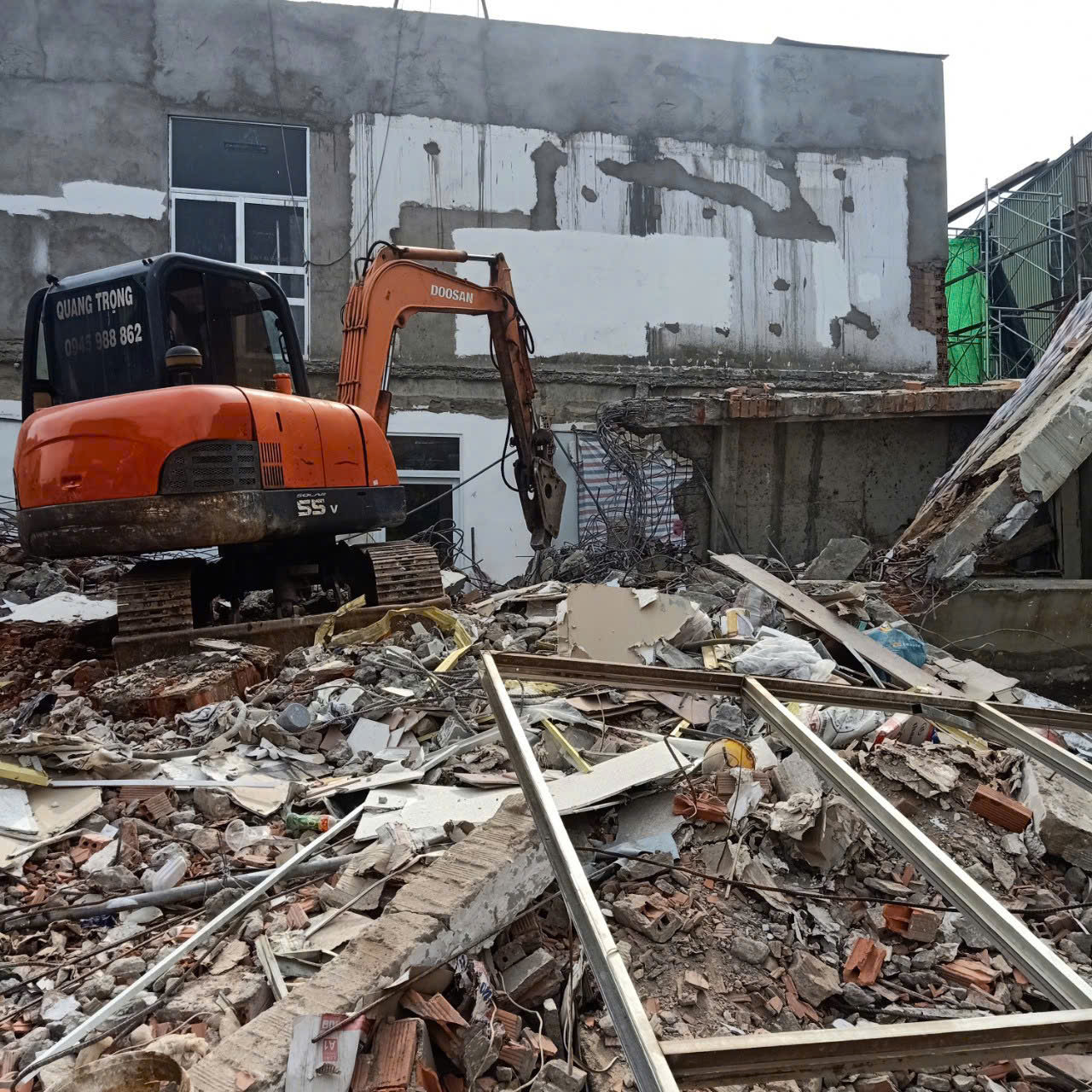 Xe cuốc gắn đầu kẹp thủy lực xử lý kết cấu tại công trình nhà đã phá dỡ một phần