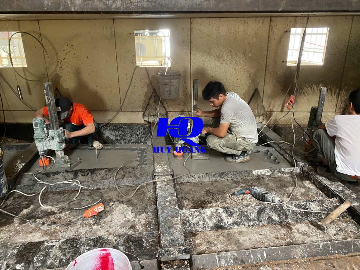 Công nhân dùng thiết bị chuyên dụng xử lý bề mặt nền công trình, đội kỹ thuật giám sát trực tiếp tại hiện trường
