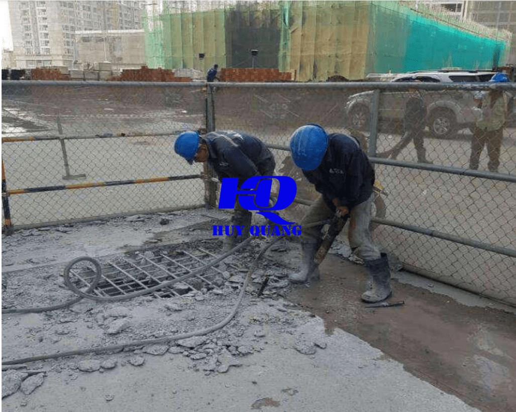 Công nhân xử lý nền và vỉa hè công trình tại khu vực đô thị, các khối nhà cao tầng phía sau
