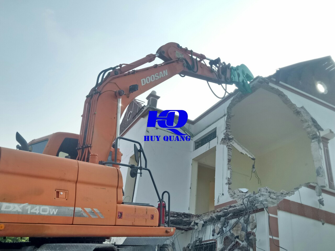 Máy xúc xử lý kết cấu tường trong quá trình phá dỡ công trình