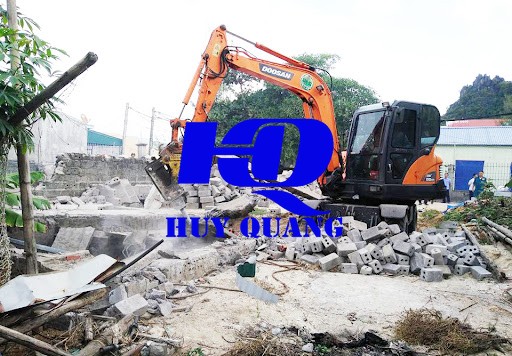 Máy đào xử lý phần khung và tường còn lại sau khi các thanh kèo thép đã được tháo dần