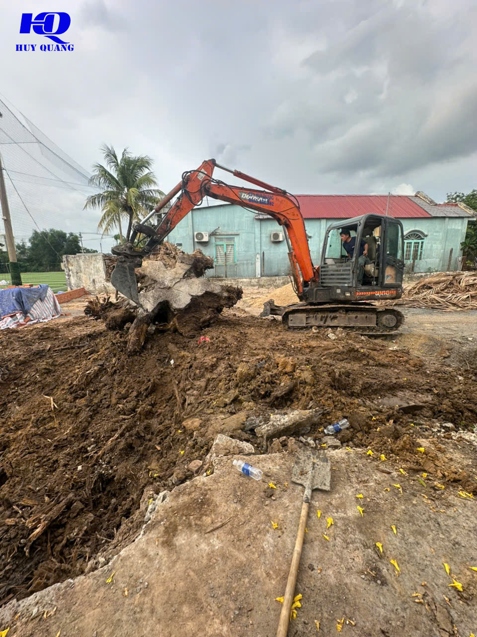 Máy đào xử lý gốc cây và mặt bằng trước nhà cấp 4 mái tôn tại khu dân cư ở Bình Dương