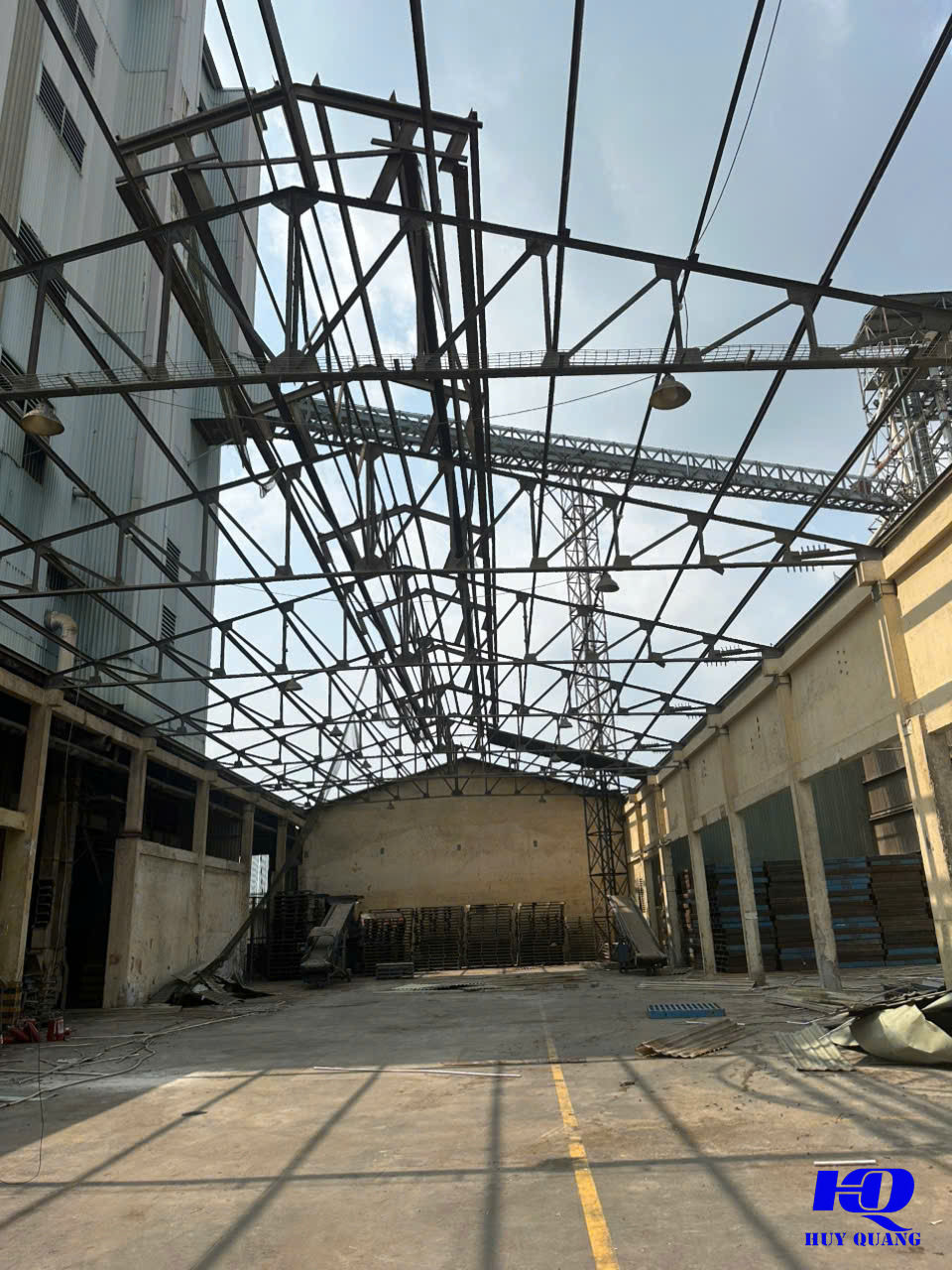 Lòng nhà xưởng đã dọn trống dưới khung kèo thép không mái, pallet xếp sát tường cuối xưởng