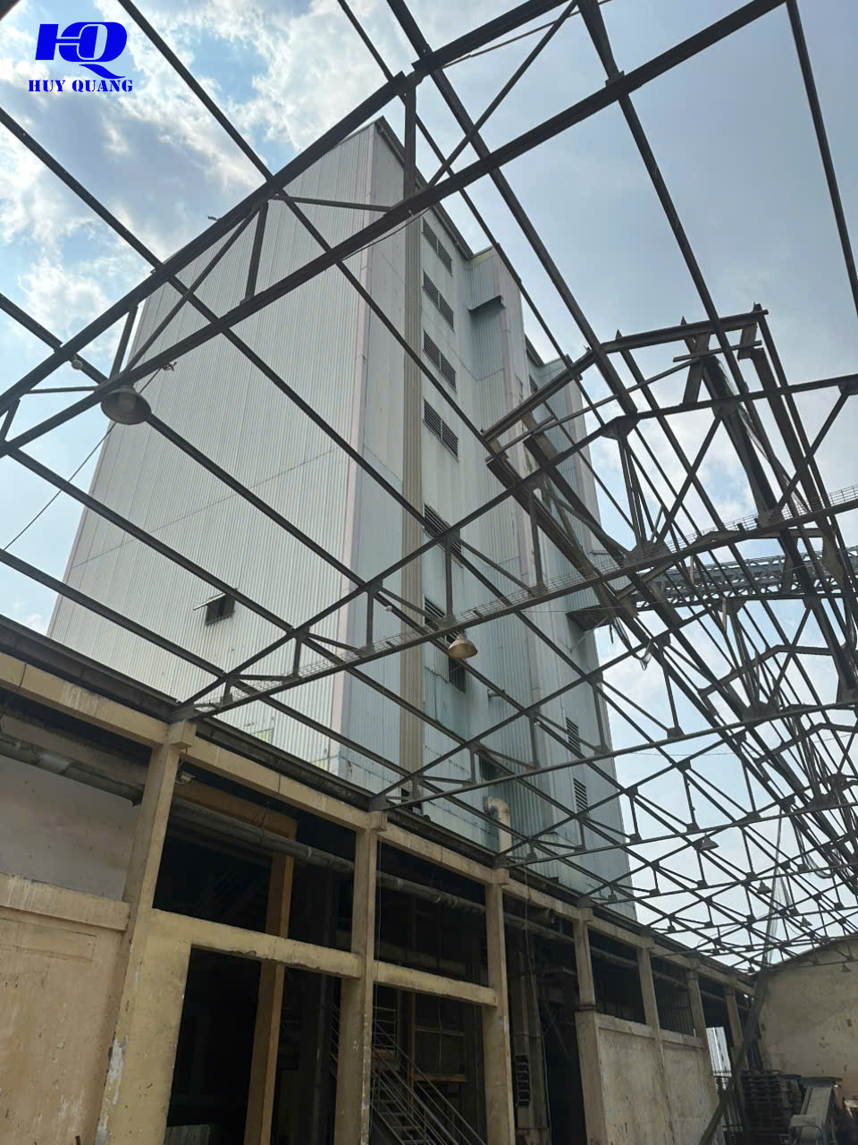 Hệ kèo thép mái đã gỡ hết tôn, chụp từ dưới lên, bên dưới là tường và cột của dãy xưởng cũ