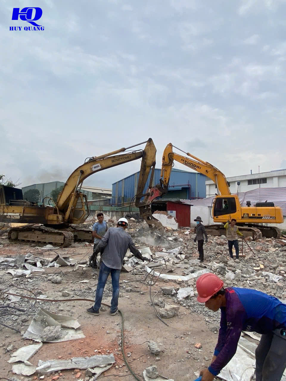 Hai máy đào gắn kẹp thủy lực phá dỡ công trình cũ, công nhân nhặt tôn và sắt vụn trên nền xà bần