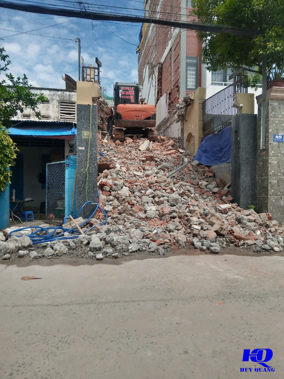 Xe cơ giới của Huy Quang phá dỡ nhà phố trong hẻm nhỏ, đống xà bần gạch vụn đổ tràn ra lối đi giữa hai căn nhà liền kề đánh số 87 và 89