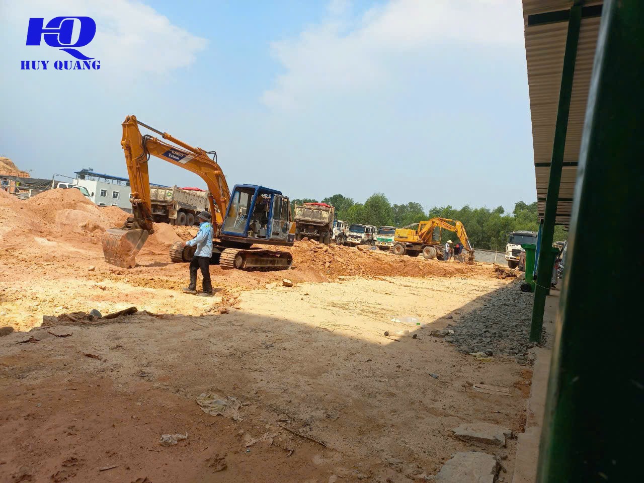 Hai máy đào và đoàn xe ben chở phế thải tại công trình giải phóng mặt bằng cạnh nhà xưởng mái tôn