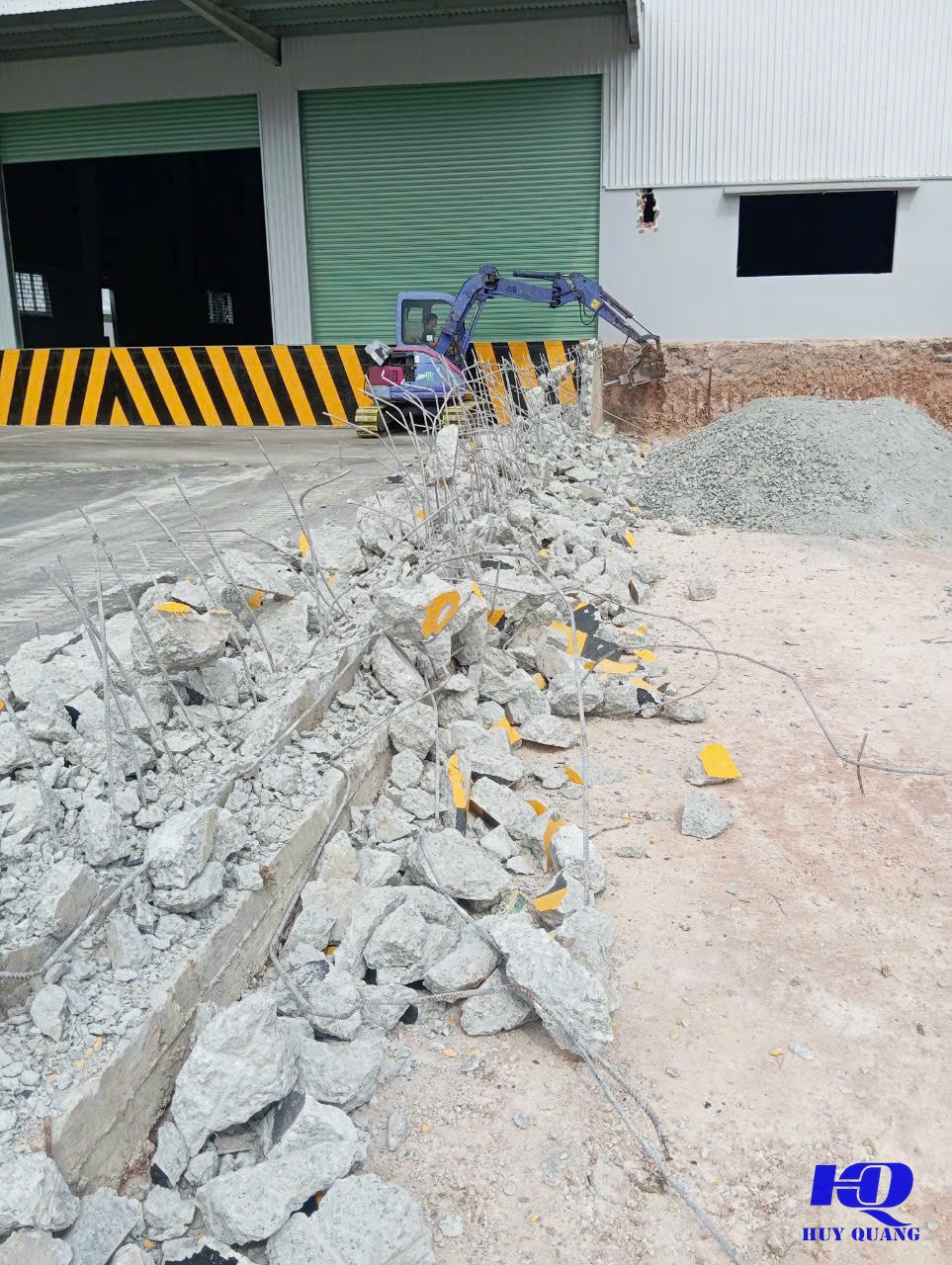 Máy khoan cầm tay đang khoan một lỗ tròn xuyên tường bê tông, dây dẫn nước làm mát nối vào máy, mạt bê tông ướt quanh miệng lỗ