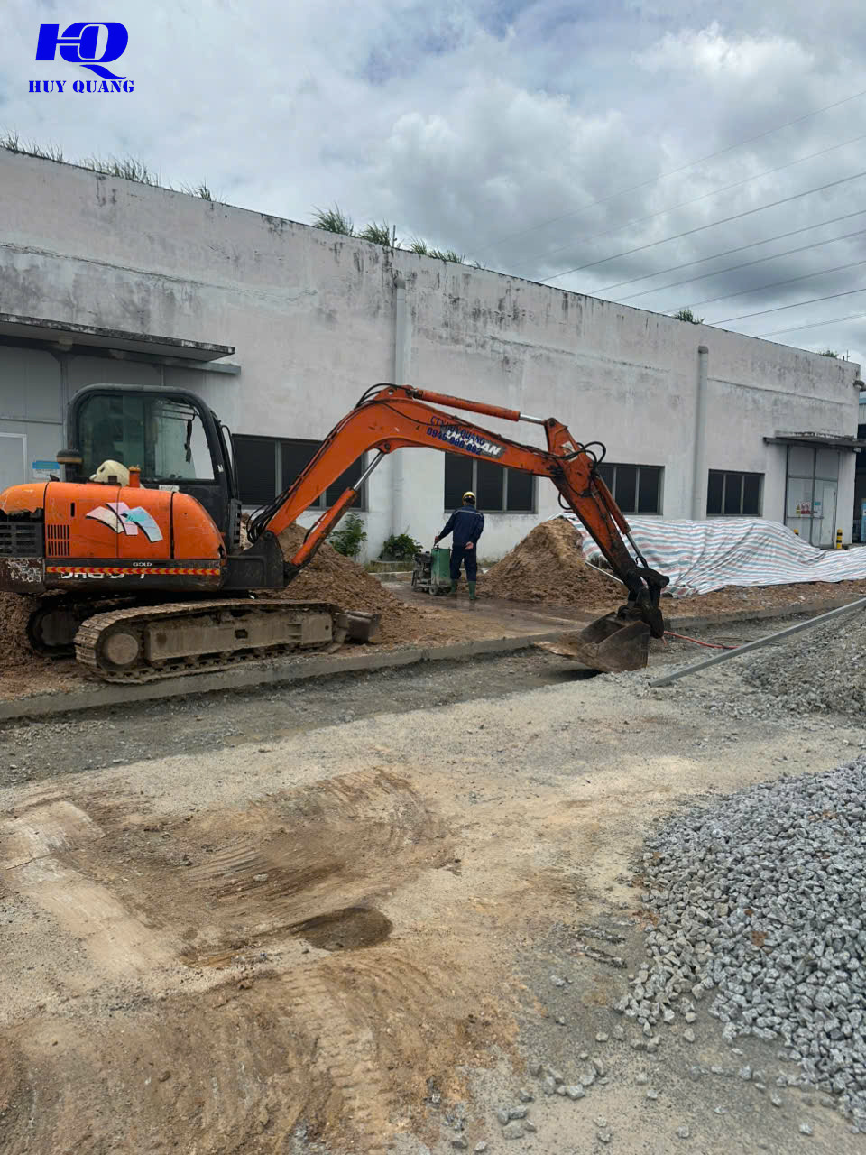 Máy đào và thợ thi công cắt bê tông trong khuôn viên nhà xưởng tại khu công nghiệp Bàu Bàng mở rộng, Bình Dương