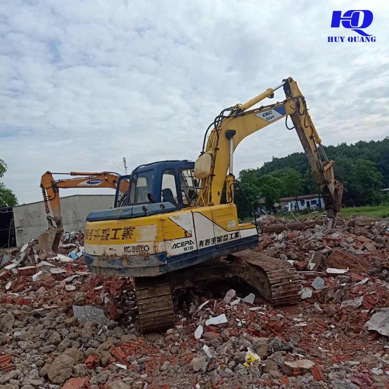 Máy đào dùng gàu xúc dọn gạch vụn và xà bần sau khi phá dỡ phần tường và mái